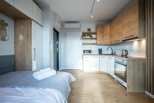 uma cozinha com armários brancos e uma cama num quarto em WiguryTower Apartaments 65 em Lódź
