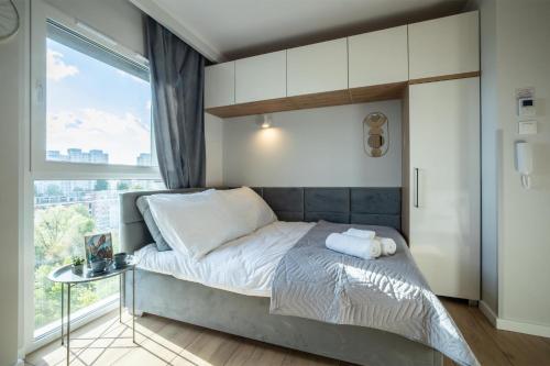 um pequeno quarto com uma cama e uma janela em WiguryTower Apartaments 65 em Lódź