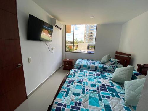 um quarto com 2 camas e uma televisão de ecrã plano em Hermoso Apto en Ricaurte con piscina em Ricaurte
