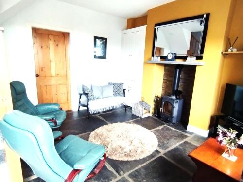 a living room with blue chairs and a fireplace at Butterside Cottage in Burtersett near Hawes in Hawes