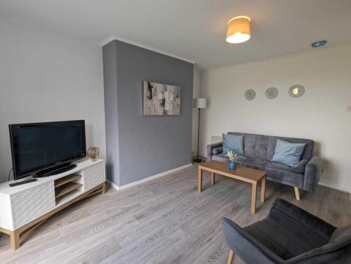 uma sala de estar com uma televisão de ecrã plano e um sofá em Alexander Apartments Dudley em Seaton Burn