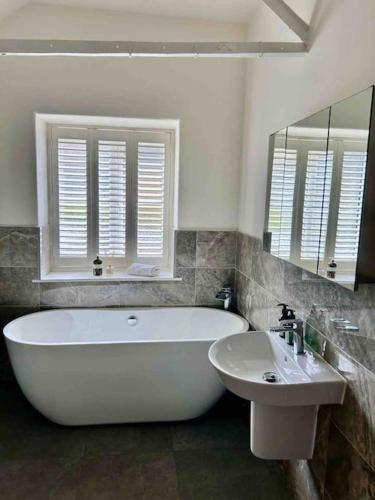a bathroom with a large tub and a sink at The Haven by MaisonPro in Gloucestershire