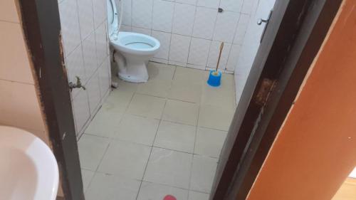 a bathroom with a toilet and a toilet brush at Meral inn Jinja in Jinja