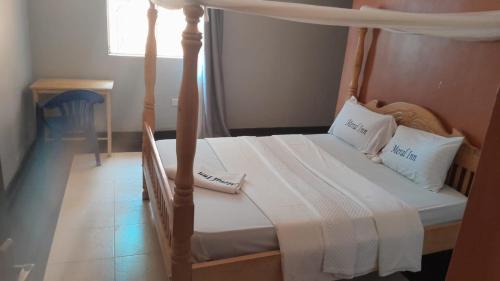 um quarto com uma cama de dossel com lençóis e almofadas brancos em Meral inn Jinja em Jinja