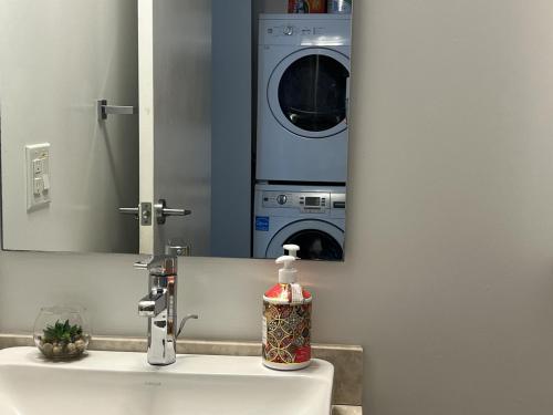 a bathroom with a sink with a washing machine in a mirror at Prime Stay Suites in Toronto