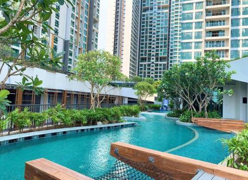 a swimming pool with benches in a city with tall buildings at Feliz apartment 1Br ThanhMyLoi in Ho Chi Minh City