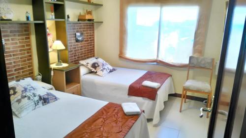een kamer met 2 bedden, een stoel en een raam bij 3 bedrooms house with private pool enclosed garden and wifi at Chatun in Chatún