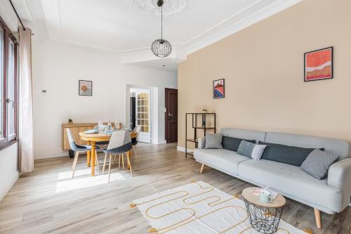 a living room with a couch and a table at Néfertiti - 3 chambres spacieuses in Saint-Étienne