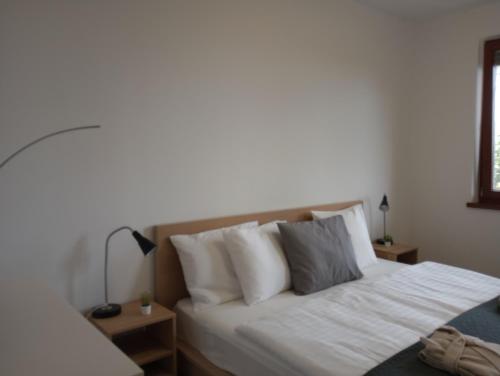 Schlafzimmer mit einem Bett mit weißer Bettwäsche und Kissen in der Unterkunft Toboz41apartman in Budapest