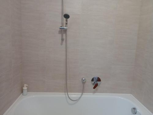 eine Dusche mit Duschkopf und eine Badewanne in der Unterkunft Toboz41apartman in Budapest