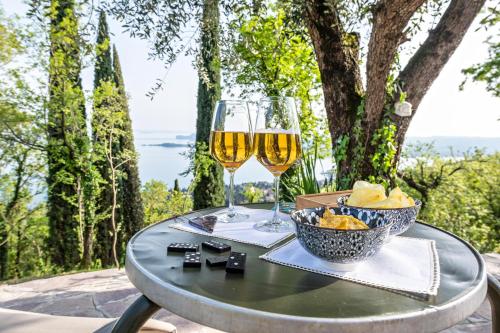 a table with two glasses of wine and a bowl of food at Villa Artista in Gardone Riviera
