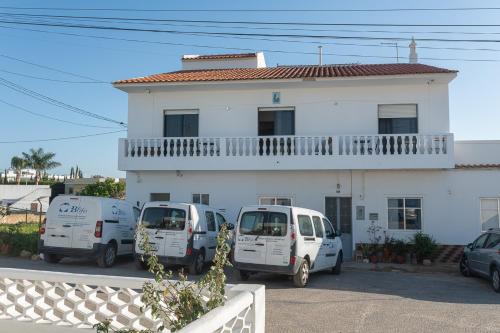 three cars parked in front of a white building at Marya private rooms in Faro