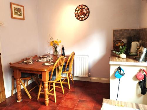 a dining room table with chairs and a clock on the wall at Butterside Cottage in Burtersett near Hawes in Hawes