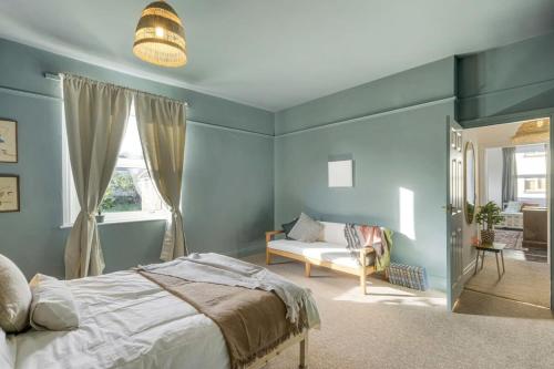 a bedroom with blue walls and a bed and a couch at Bright Apartment w Parking & Distant Sea Views in Minehead