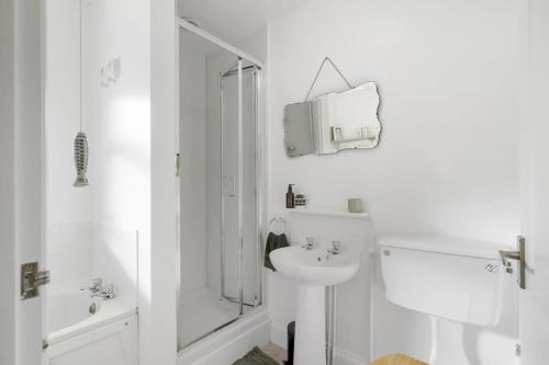 a white bathroom with a shower and a sink at Bright Apartment w Parking & Distant Sea Views in Minehead