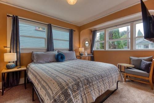 a bedroom with a bed and a chair and windows at #StayinMyDisctrict Historic Heritage House Apt in Coos Bay