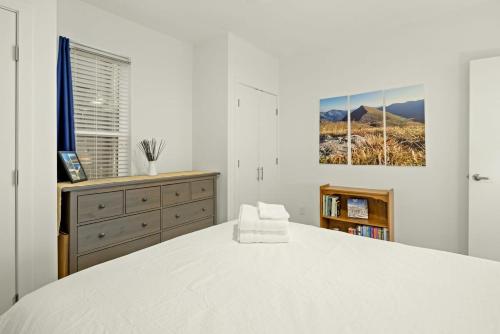 1BR City Park Stay Medical District 30 Day في دنفر: غرفة نوم بيضاء مع سرير أبيض وخزانة