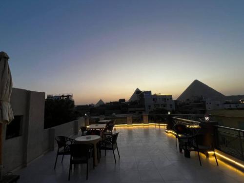 een dakterras met tafels en stoelen en piramides bij lsis pyramids view in Caïro