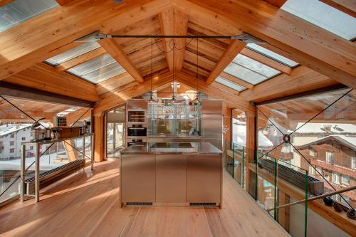 an open kitchen with wooden ceilings and glass windows at Luxury Chalet by Heinz Julen in Zermatt