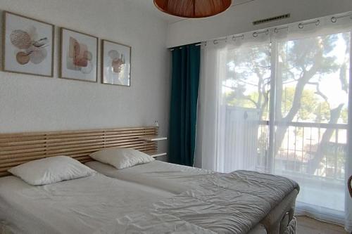 a bedroom with a bed and a large window at Les Géraniums, bel appartement rénové, proche plage et commerces in La Seyne-sur-Mer