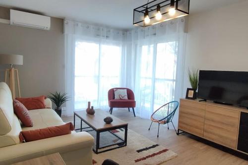 a living room with a couch and a tv at Les Géraniums, bel appartement rénové, proche plage et commerces in La Seyne-sur-Mer