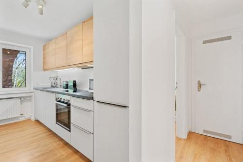 a kitchen with white cabinets and a wooden floor at Chic Apt Close to Kirchberg Shopping Centre ID157 in Luxembourg