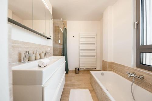 een witte badkamer met een wastafel en een bad bij City Luxury with City Views in Ville Haute ID174 in Luxemburg