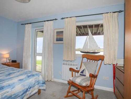 een slaapkamer met een bed en een zeilboot in het raam bij Waters Edge Ymyl Y Dwr in Y Felinheli