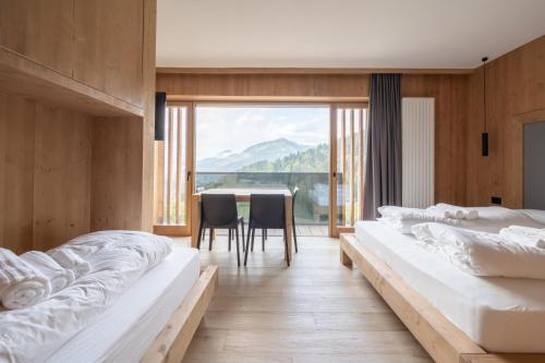 two beds in a room with a table and chairs at aMa Dolomiti Resort in Vigo di Cadore