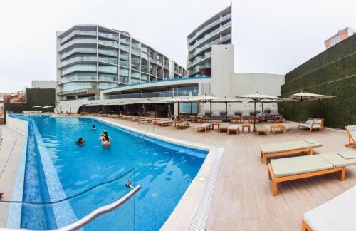 una piscina con mesas y sillas y un edificio en Hermoso apartamento en Ocean Reef San Bartolo, con acceso piscina y área sociales!, en San Bartolo