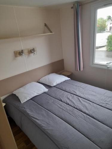 two beds in a small room with a window at Mobil Home 6 couchages in Vic-la-Gardiole