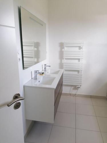 une salle de bain blanche avec un lavabo et un miroir dans l'établissement Maison familiale 120 m2 à 15 minutes de la mer, à Lanmeur
