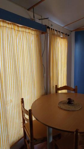 a dining room table and chairs with a table and curtains at Lands House Bungalows in Pataias