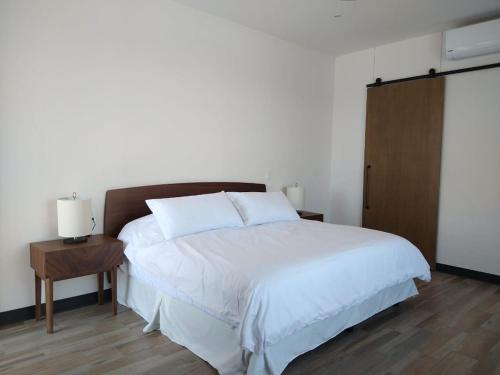 - une chambre dotée d'un lit blanc avec une table de chevet et une table de chevet dans l'établissement Suite Loft Amplio Nuevo Salida a CDMX 204A, à Querétaro