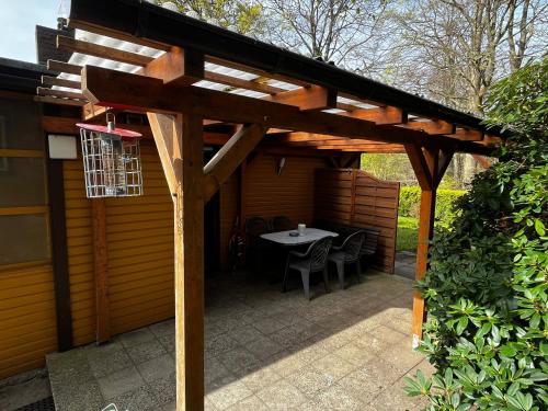 a wooden pergola with a table in a patio at Strand und Waldhaus in Ückeritz Uriges Ambiente trifft Meer in Ueckeritz