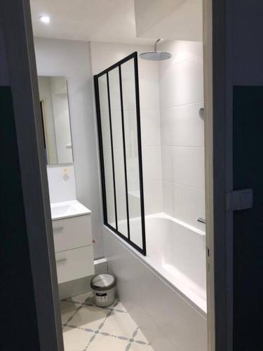 une salle de bain blanche avec une baignoire et un lavabo dans l'établissement Le beau T4 Côte Pavée parking facile, à Toulouse