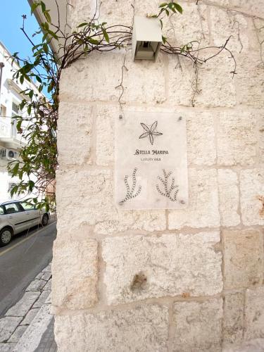 a sign on the side of a stone wall at Stella Marina Luxury in Polignano a Mare