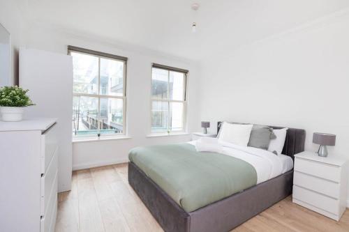 a white bedroom with a large bed and windows at Old Street - 4BR Townhouse with Patio - CityApartmentStay in London