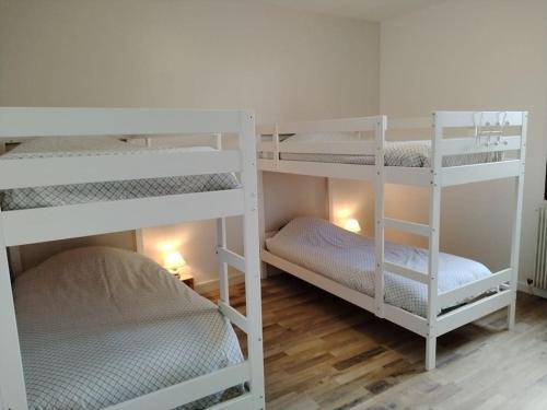 2 weiße Etagenbetten in einem Zimmer mit Holzböden in der Unterkunft Au gîte Sérénité in Mouthier-en-Bresse