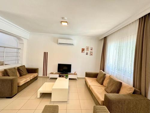 a living room with a couch and a tv at Anfora Villaları in Belek