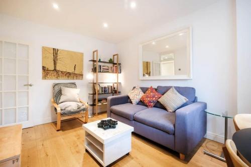 sala de estar con sofá azul y silla en Shoreditch Park & Islington - CityApartmentStay en Londres