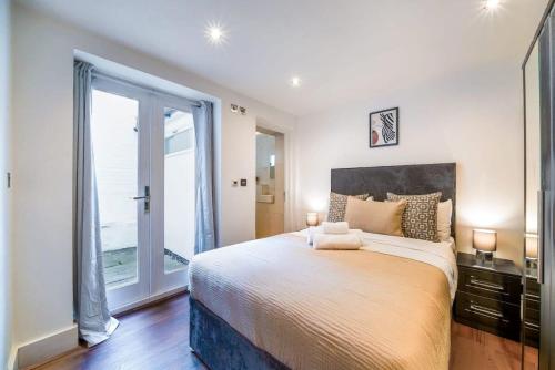 um quarto com uma cama grande e uma janela grande em Notting Hill & Hyde Park - CityApartmentStay em Londres