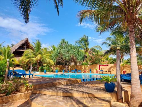 un complejo con una piscina con palmeras en Queen of Sheba Beach Lodge, en Pongwe