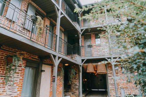 un edificio de ladrillo con balcones y una puerta negra en Apparts' Rennes BnB Duhamel- Centre Gare, en Rennes