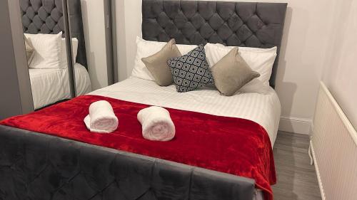 - un lit avec une couverture rouge et quelques oreillers dans l'établissement SAV 3 Bedroom House Chiltern Rise Luton, à Luton