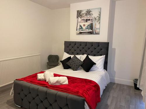 - une chambre avec un grand lit et une couverture rouge dans l'établissement SAV 3 Bedroom House Chiltern Rise Luton, à Luton