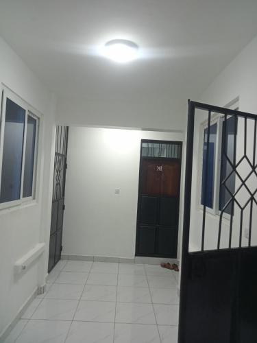 een lege kamer met een deur en een tegelvloer bij Hmy in Mombasa