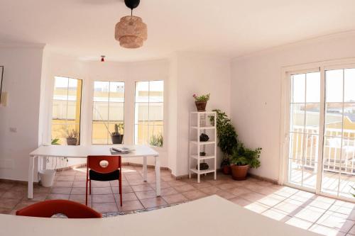 a white room with a table and chairs and windows at Integral Coliving Surf Yoga House in El Médano