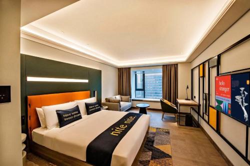 a hotel room with a large bed and a couch at MUSTEL Hotel Guangzhou Nansha in Guangzhou