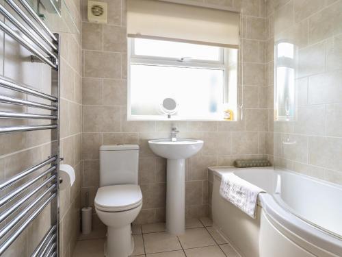 a bathroom with a toilet and a sink and a bath tub at Bryn Eithin in Benllech